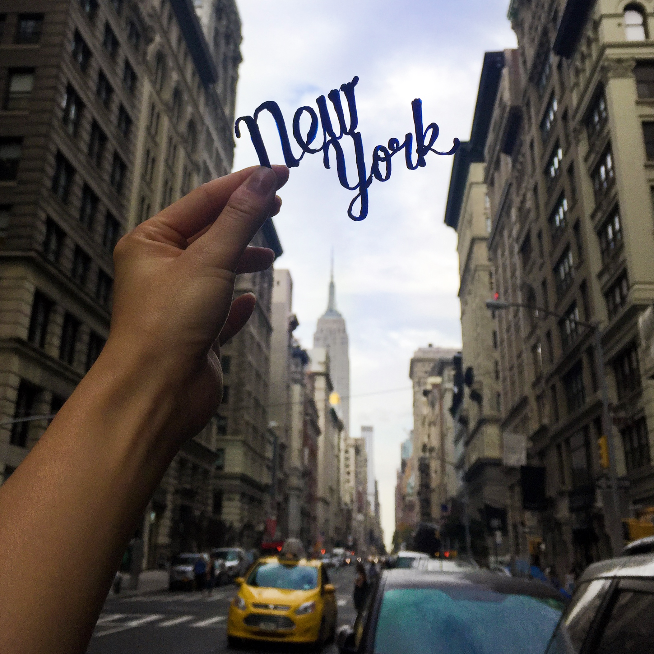 3D pen art: Someone holds up a 'New York' sign in cityscape design.